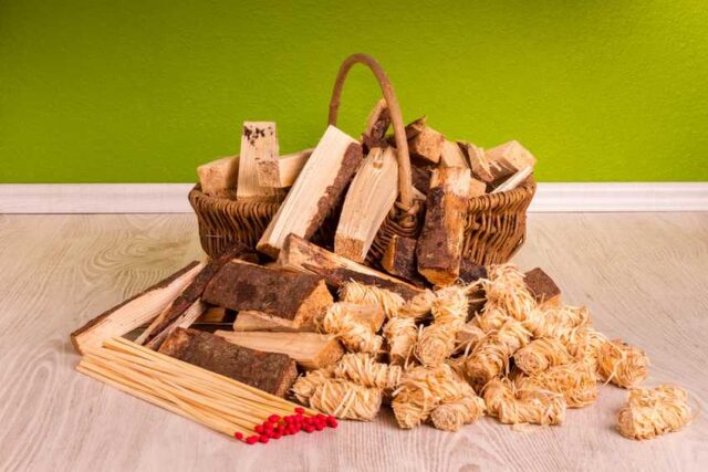 Korb Mit Anzündholz Und Streihölzern Auf Hellem Parkett Vor Grünem Hintergrund