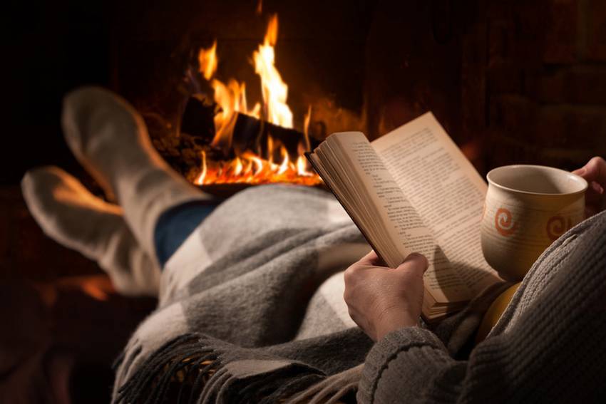 Woman Reads Book Near Fireplace